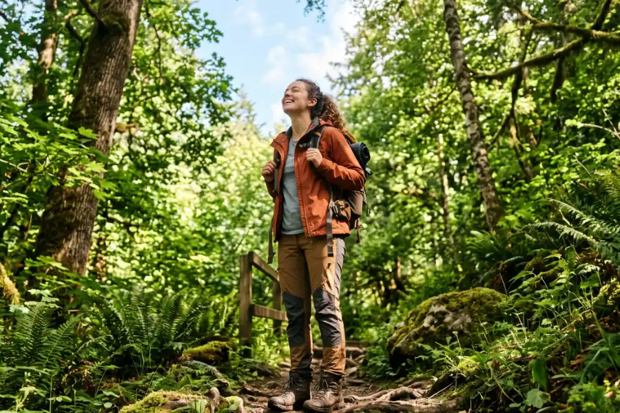 Person with a backpack standing on a wooded trail
